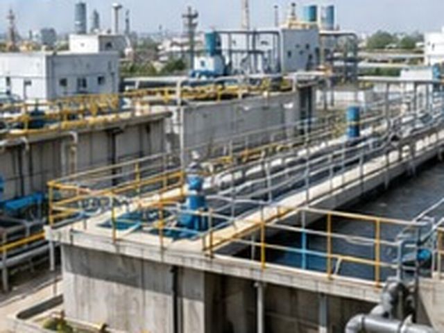 Industrial treatment plant with storage tanks beside a lagoon